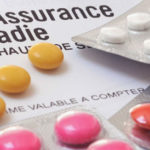 Carte Vitale de l'Assurance Maladie posée à côté de plaquettes de médicaments colorés