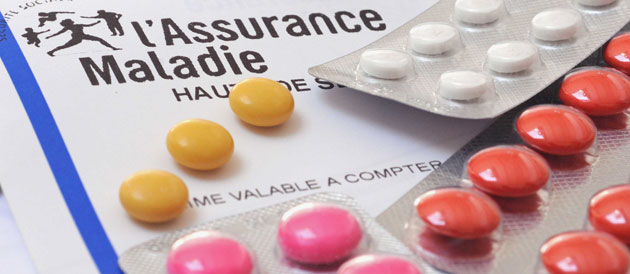 Carte Vitale de l'Assurance Maladie posée à côté de plaquettes de médicaments colorés