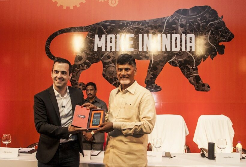 Hugo Barra and an Indian official jointly holding a Xiaomi device in front of a Make in India backdrop