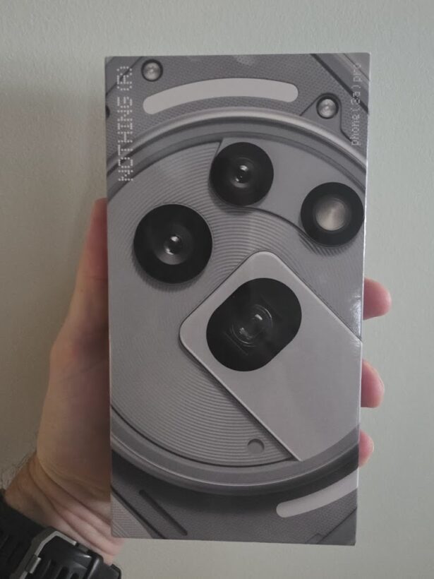 Hand holding the Nothing Phone (3) Pro retail box, showing the camera system graphic on the packaging