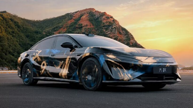 BYD Great Han flagship sedan in artistic camouflage wrap with Han badging, photographed at sunset against a mountain backdrop