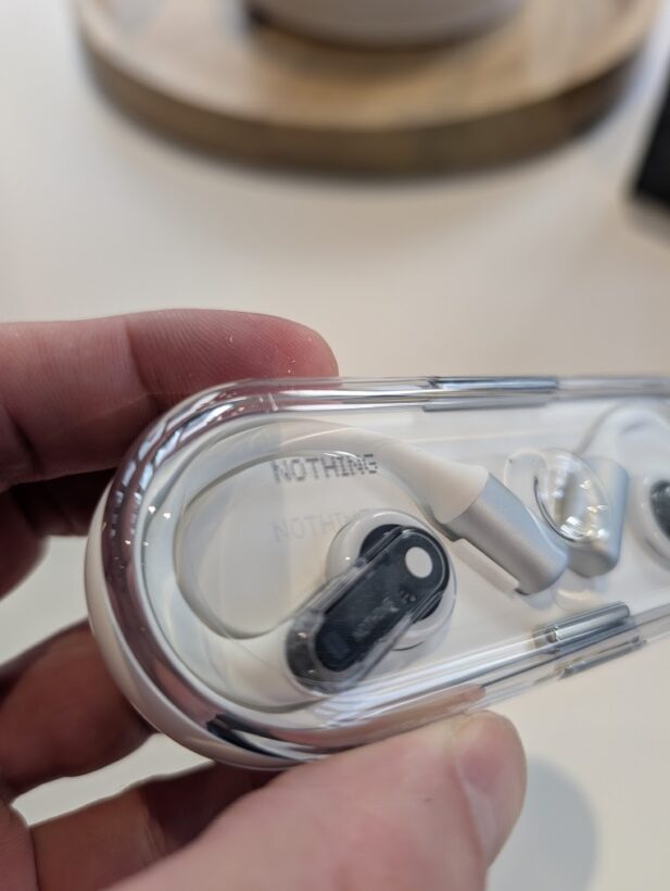 Nothing Ear earbuds in their transparent charging case, showing the signature see-through design the author chose not to buy first