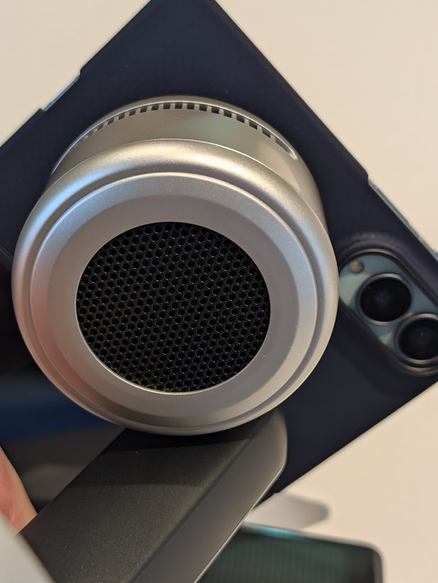 UGREEN 3-in-1 charging stand's round magnetic pad with Peltier cooling vents, holding an iPhone in a dark case